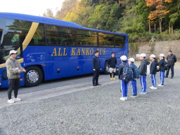 バスの前に生徒たちと先生が向き合って出発式をする様子